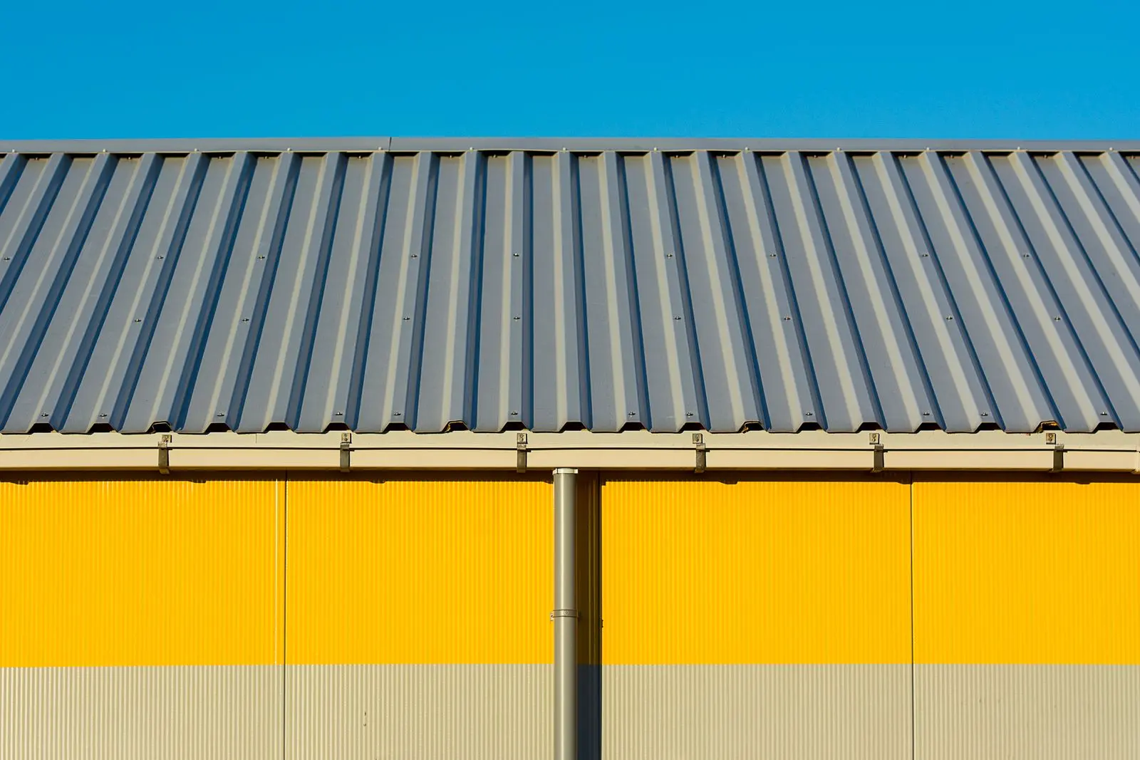 Façade d'entrepôt jaune sous toiture métallique