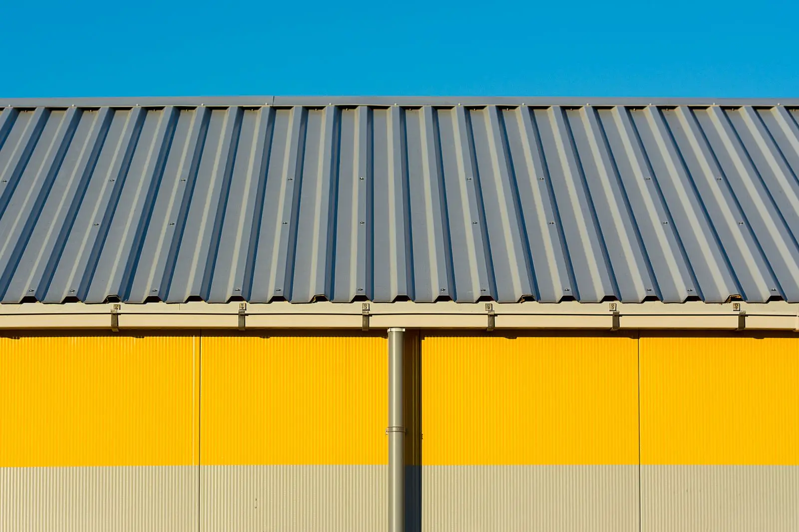 Façade d'entrepôt jaune sous toiture métallique