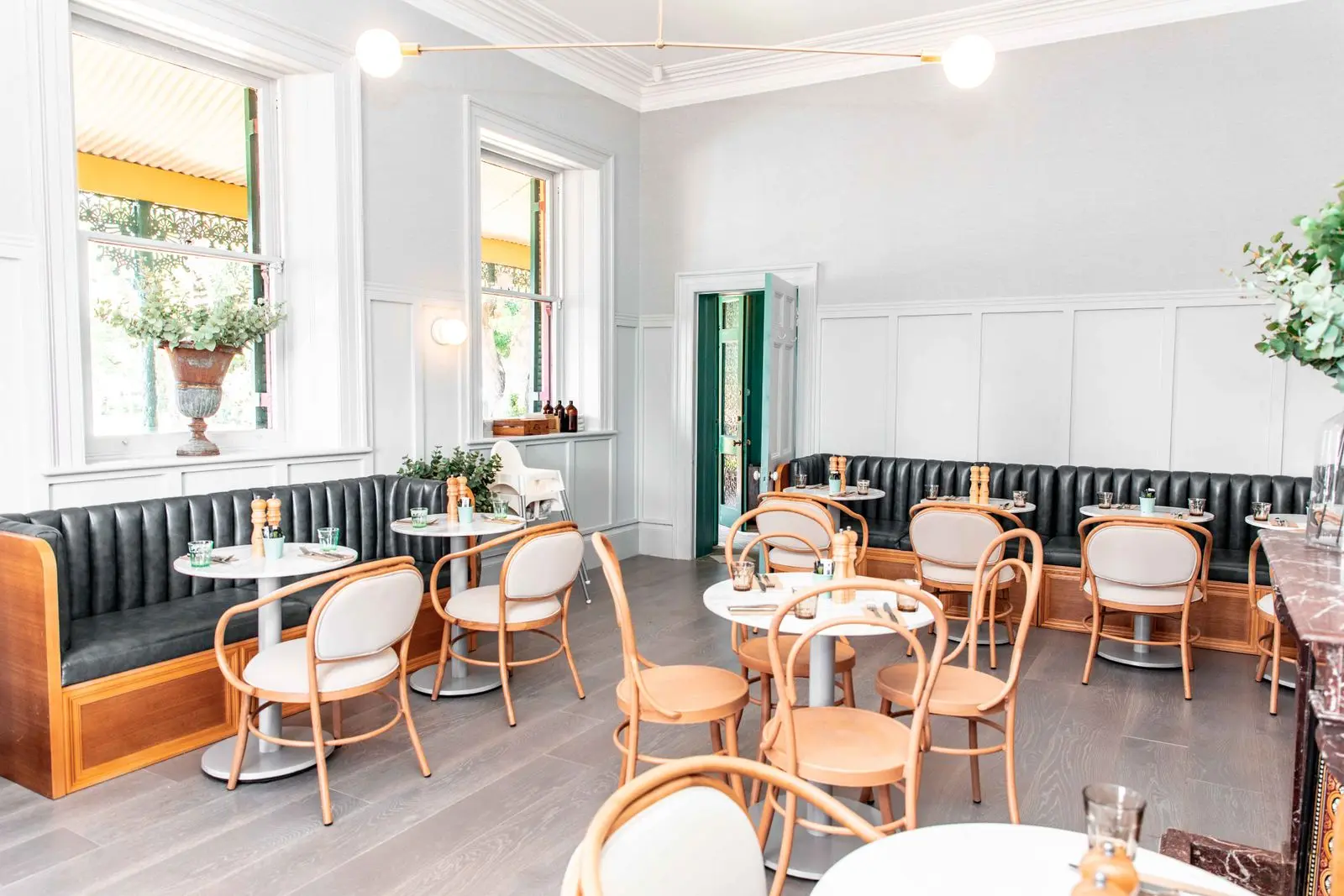 Café lumineux aux banquettes et chaises en bois courbé
